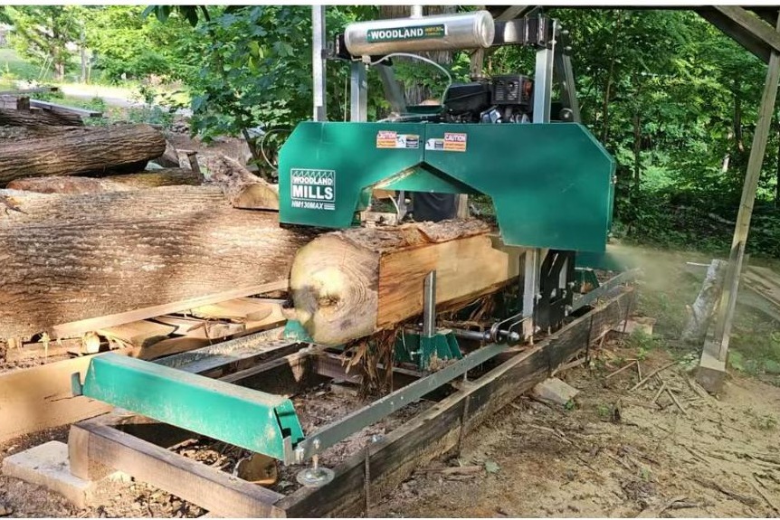 Woodland Mills HM130MAX portable bandsaw mill cutting a hardwood log, sawdust flying