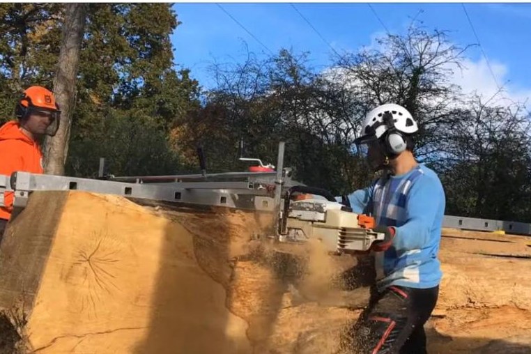 Alaskan chainsaw mill milling a slab, the guide bar running horizontally across the log