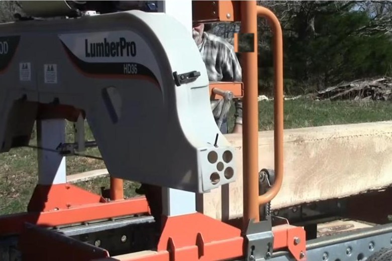 A portable bandsaw sawmill with a freshly milled flat log face, showing the clean thin-kerf cut